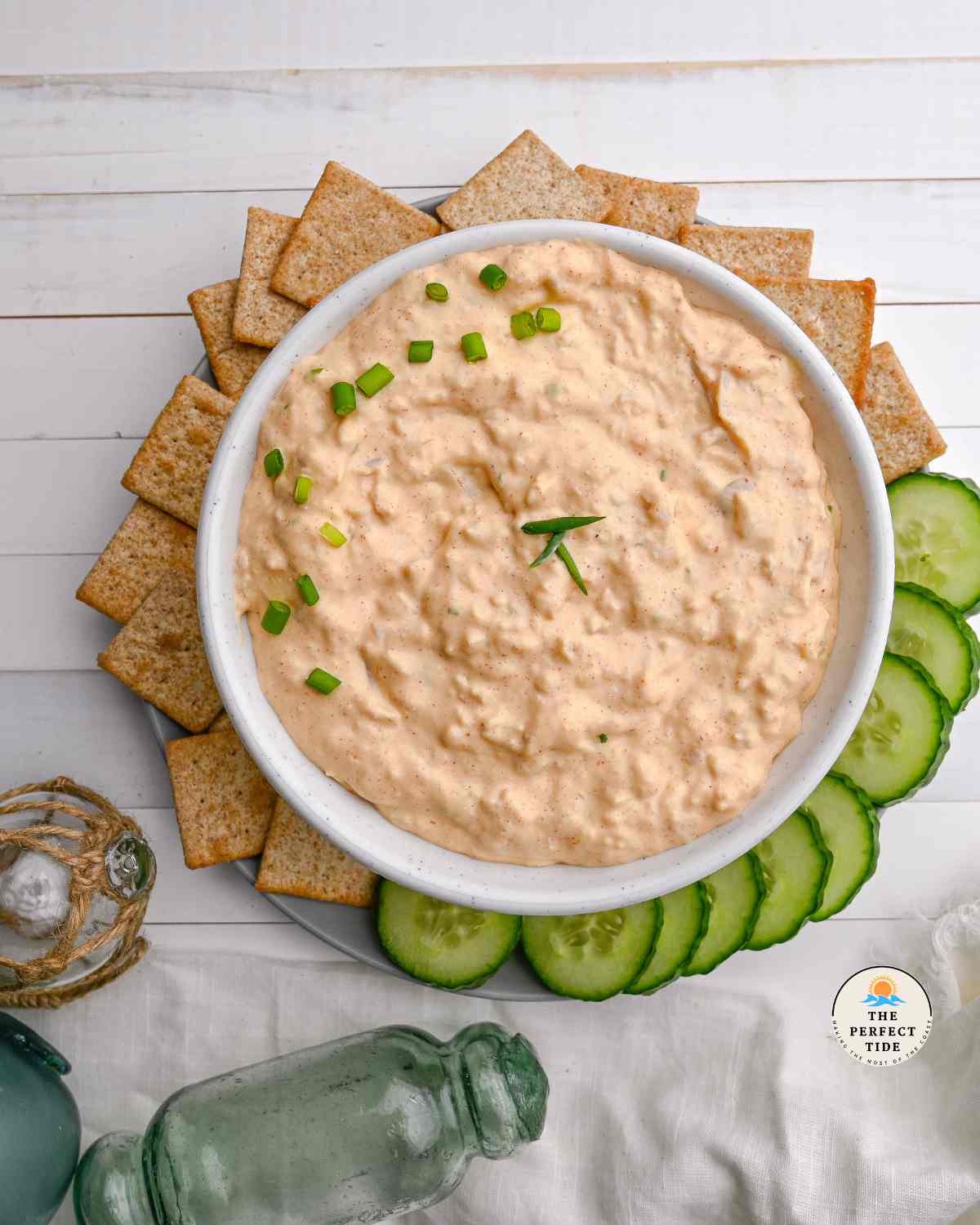 clam dip recipe in a white bowl with cucumbers and crackers around