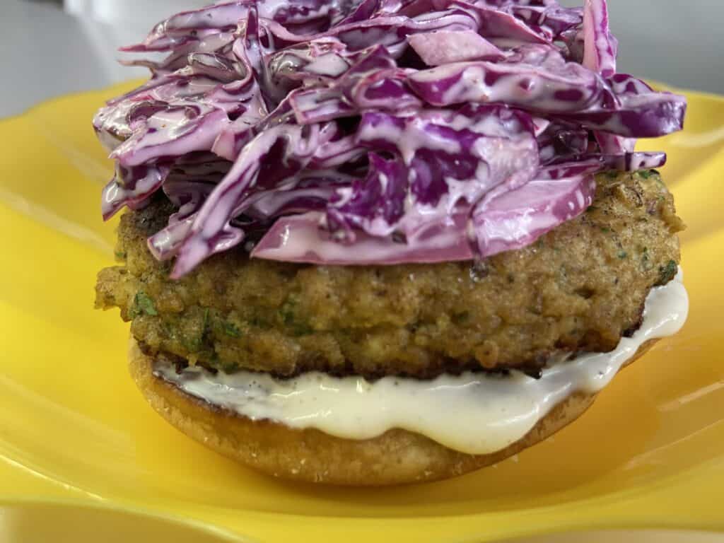 seafood burger with purple coleslaw on yellow plate