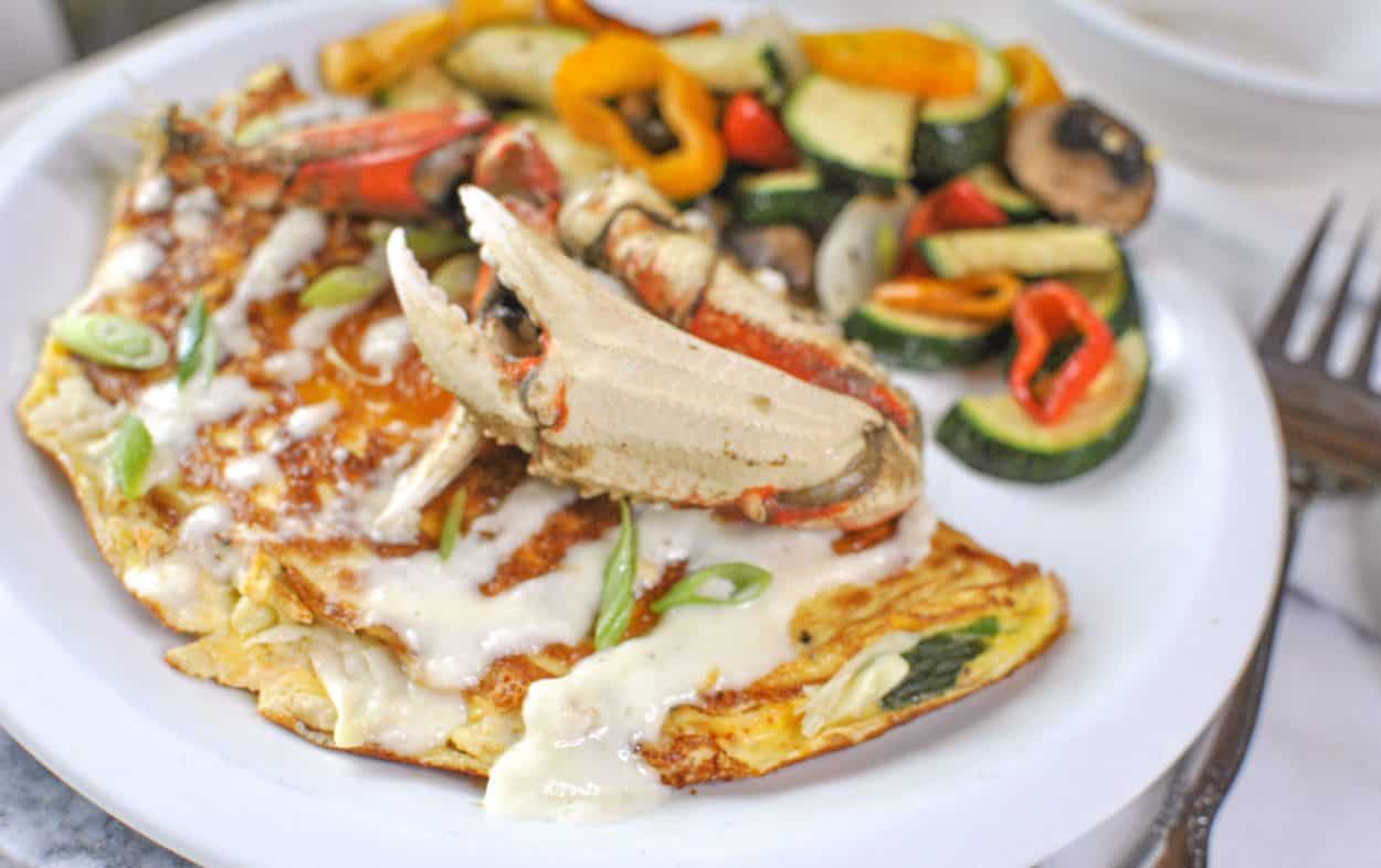 crab leg on crab omelette with roasted veggies on the side