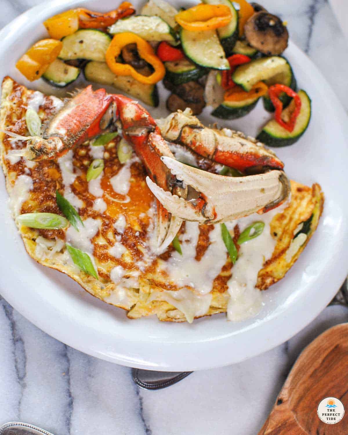 crab omelette with crab legs to garnish on white plate with grilled veggies