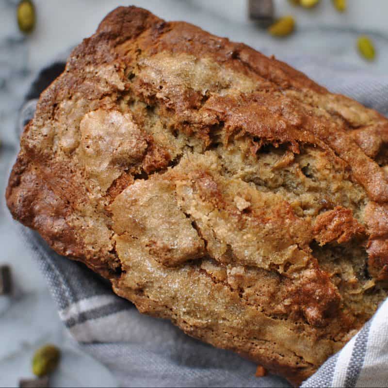 banana bread with pistachios tahini chocolate wrapped in towel marble background