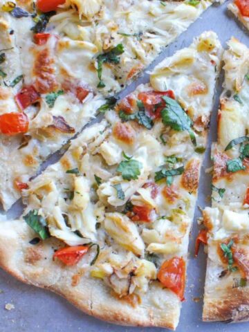 sliced creamy crab pizza with fresh tomatoes and basil