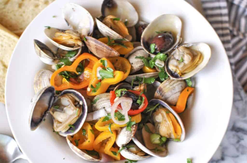 Clam bake recipe with fresh steamer clams mini peppers shallots kalamata olives with a side of bread