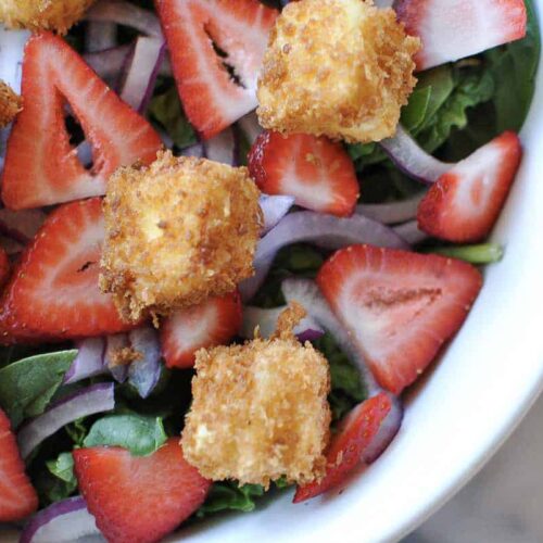 Spinach strawberry and fried feta salad in a white bowl