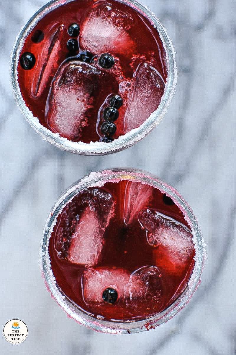 fresh huckleberries margaritas on marble countertop in clear gobler glass