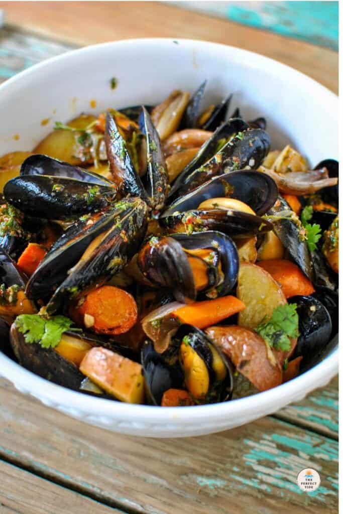Tender baked mussels and roasted root vegetables with a tasty Mediterranean chimichurri sauce in a white bowl with cilantro. Baked Mussels recipe