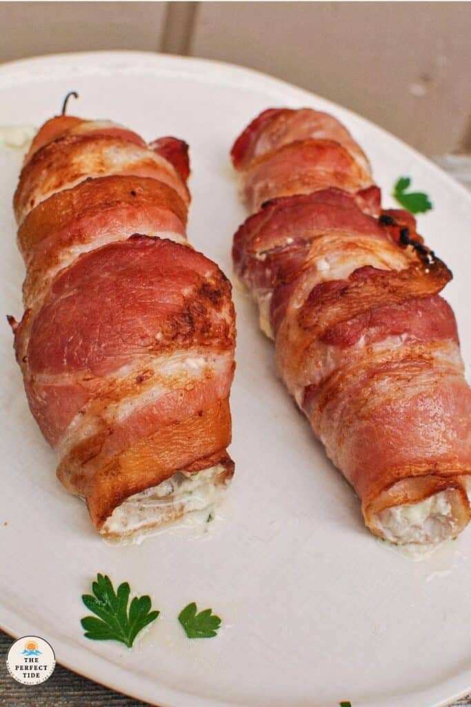 bacon wrapped boursin stuffed fish recipe with parsley garnish on white plate on wood