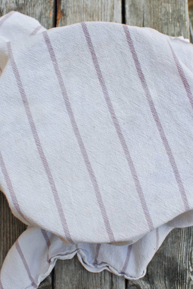towel with purple striped over bowl of dough proofing