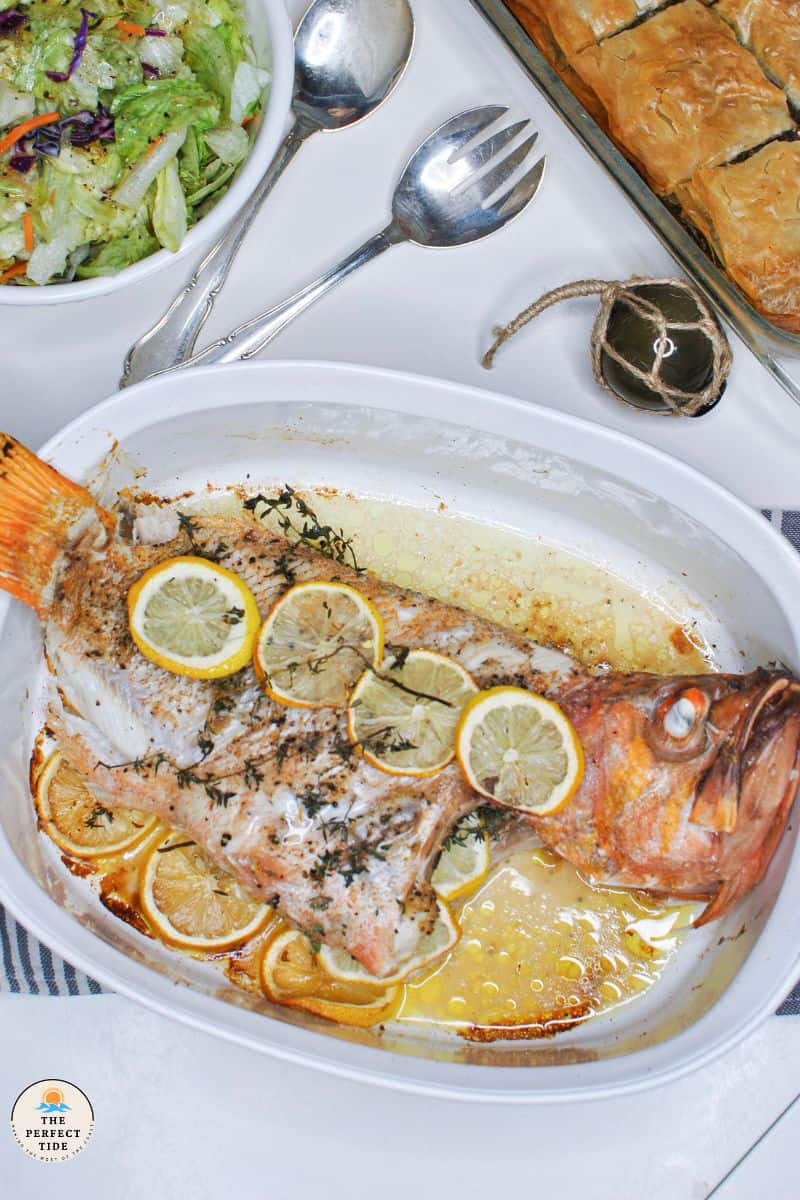 baked whole orange rockfish with side dishes spanakopita and green salad | green glass float