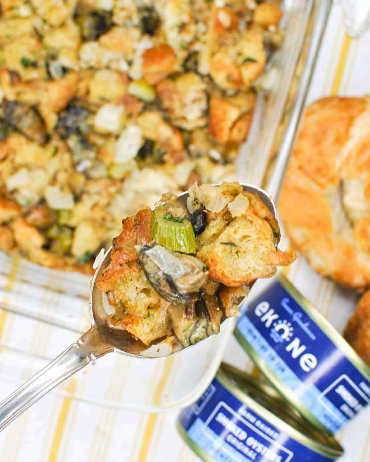 spoonful of seafood croissant stuffing with ekone canned smoked oysters to the side along with the stuffing dish