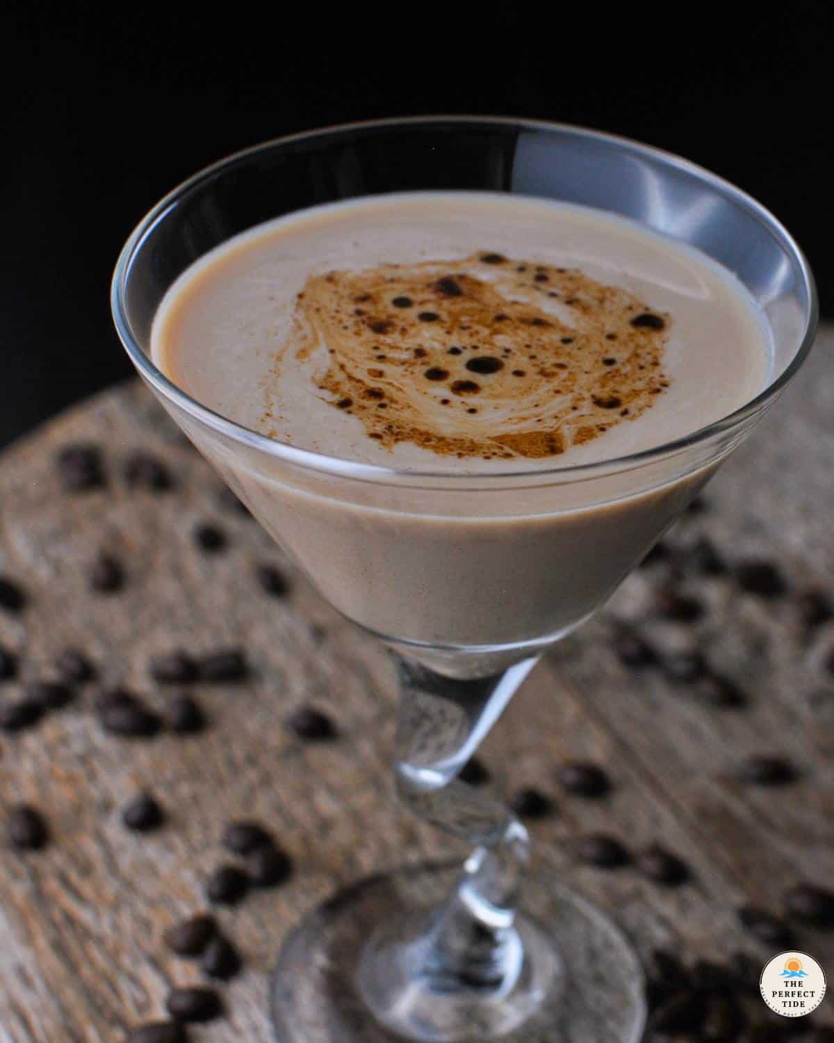 creamy espresso martini with baileys in a martini glass with coffee beans around