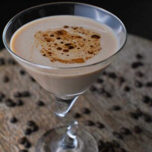 creamy espresso martini in a martini glass surrounded by coffee beans
