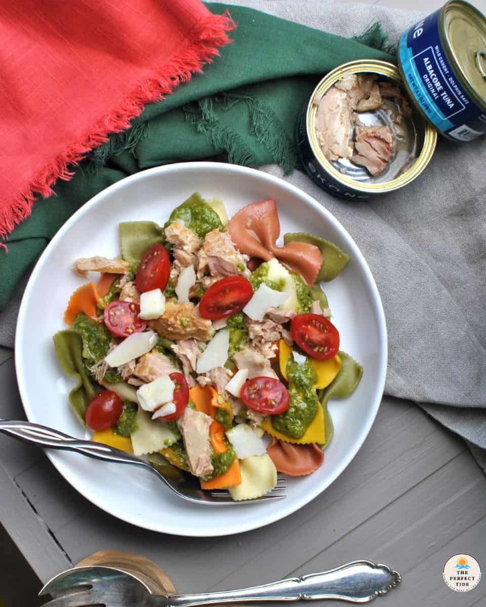 pesto pasta tuna on plate with opened canned tuna and dinner napkins