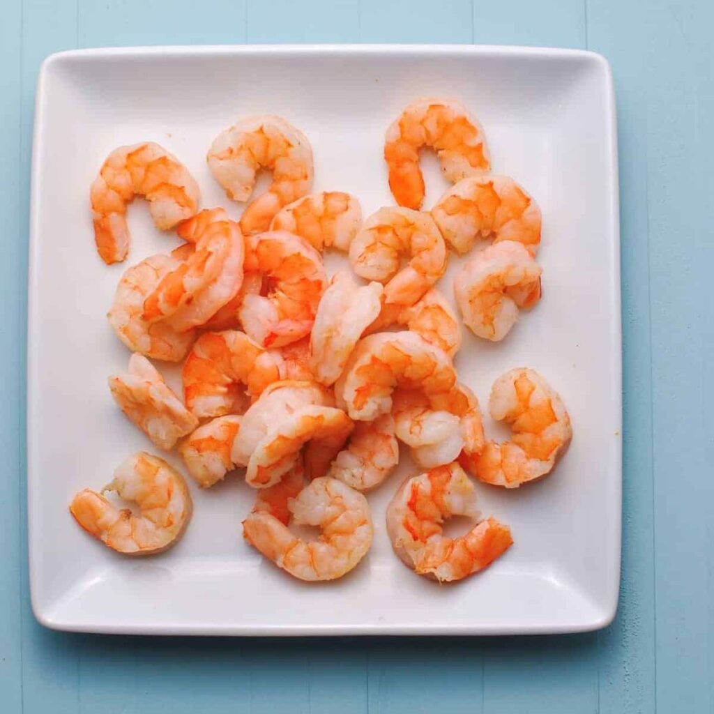 Shrimp Cooked in the air fryer on a white plate with a blue background