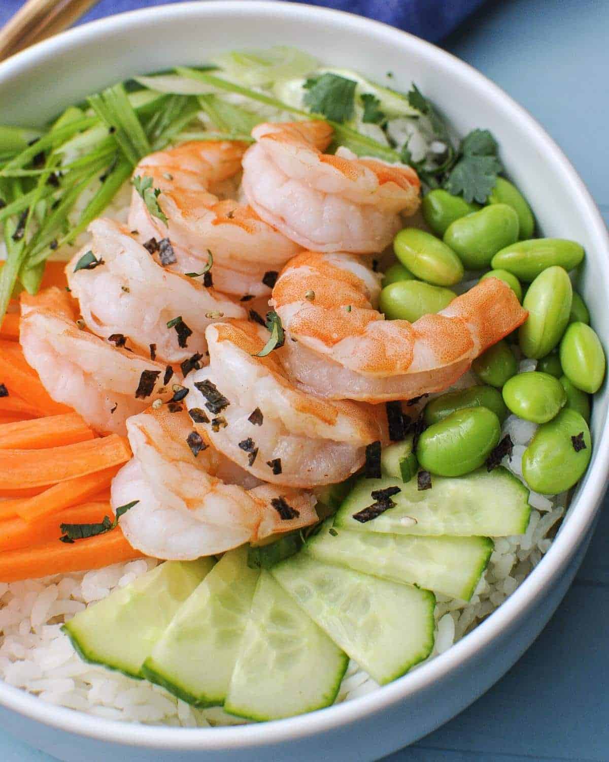 poke bowl with shrimp, edamame, cucumber, carrots, green onion over rice