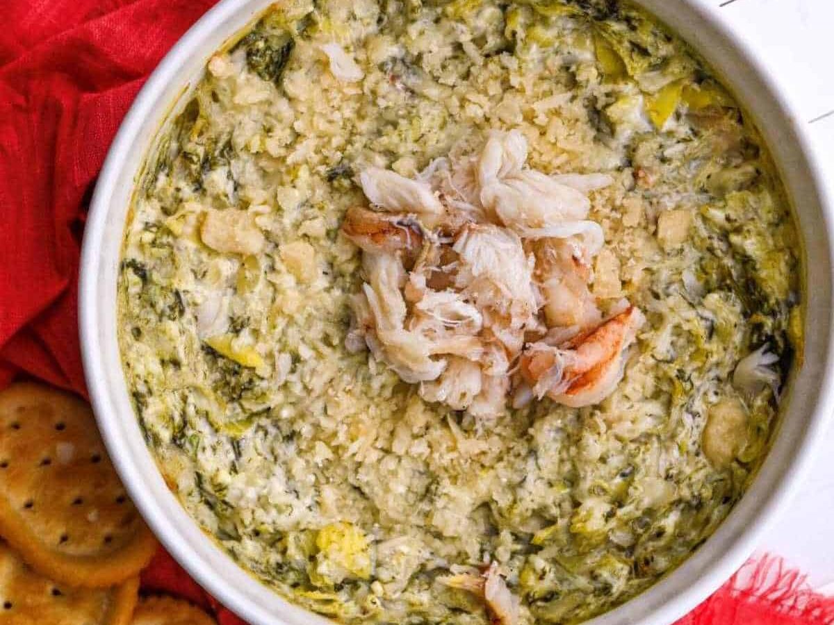 crab spinach artichoke dip topped with more crab served with crackers
