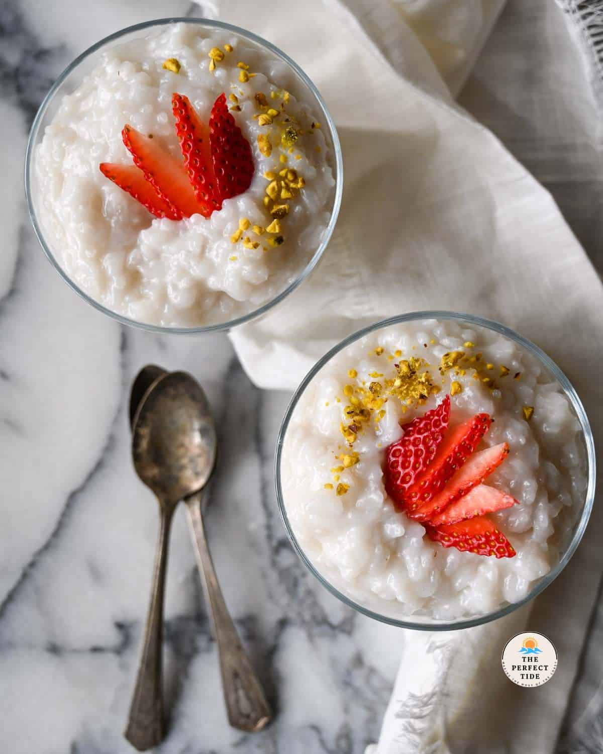 lebanese rice pudding in glass jars with strawberry and pistachios as garnish