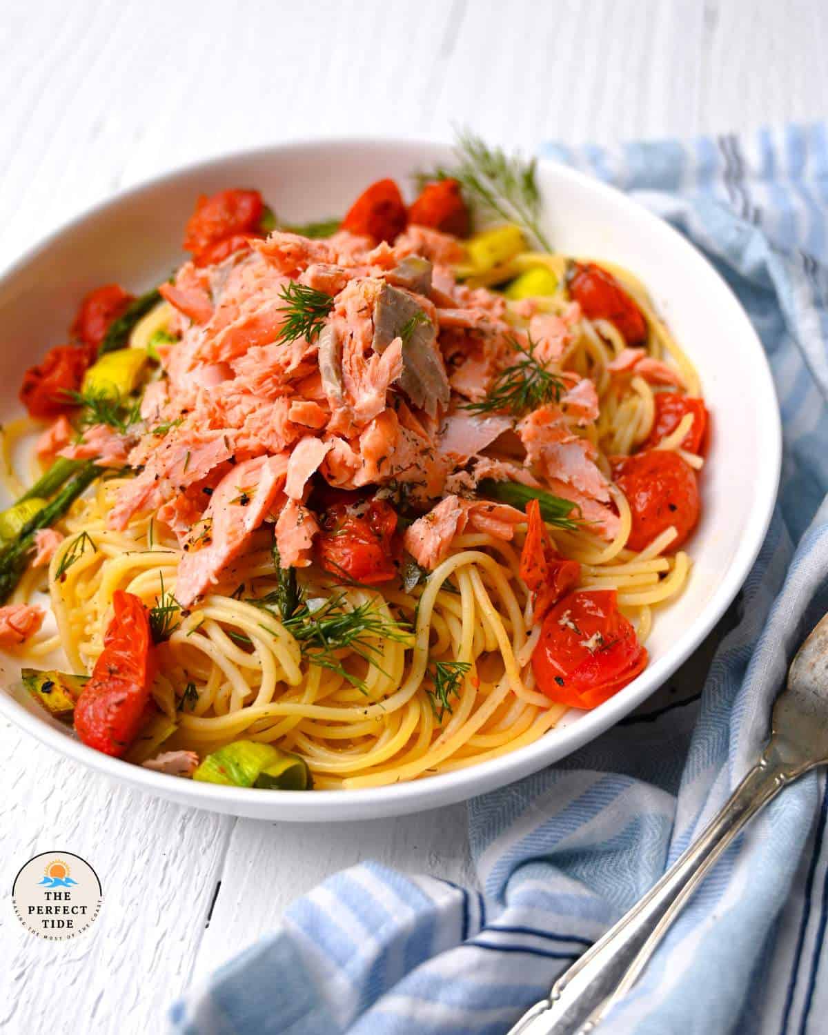 salmon pasta without cream in white dish with fork and blue towel