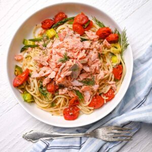 overhead of salmon pasta without cream in white dish with fork and blue towel