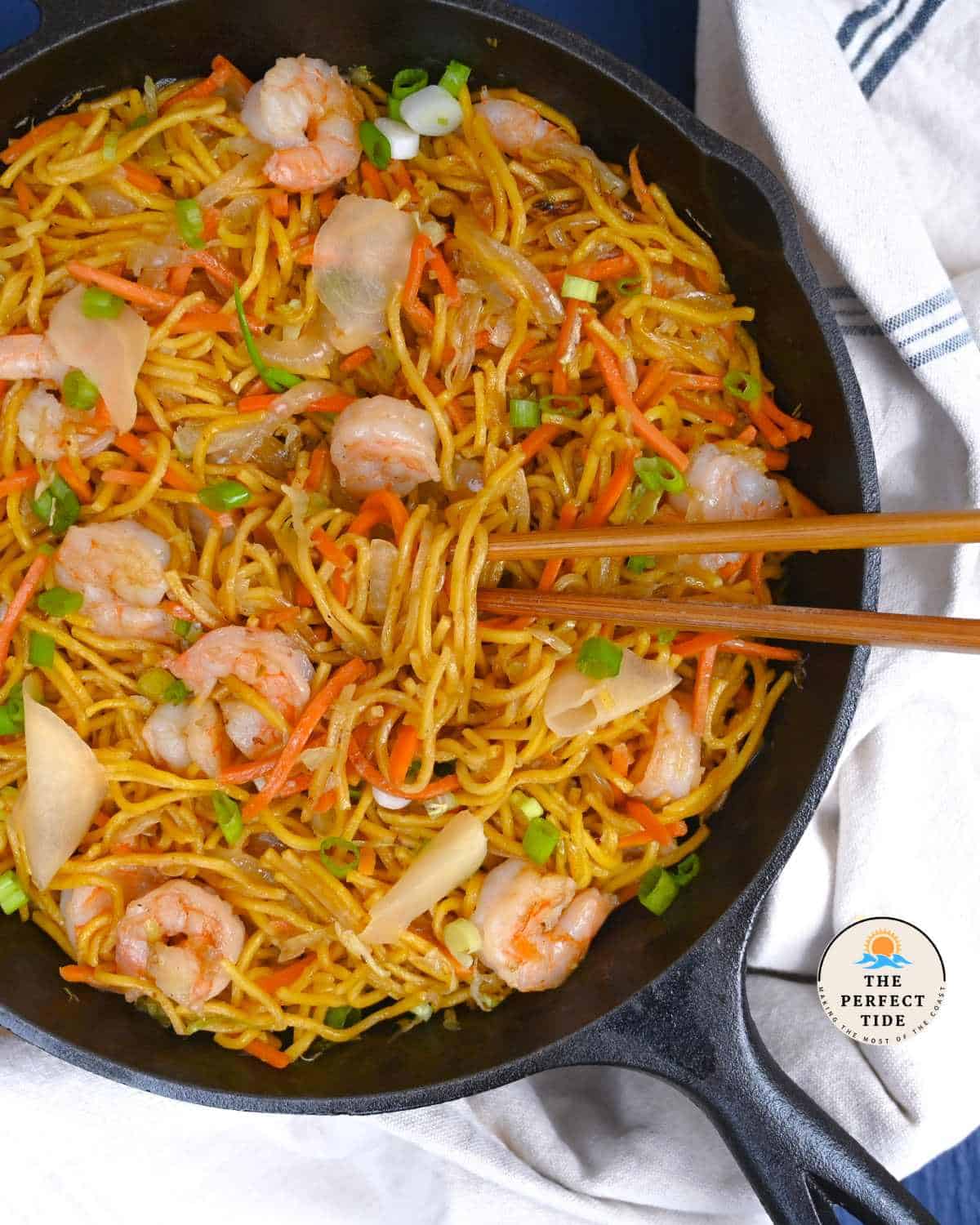 shirmp yakisoba stir fry in a large cast iron with chopsticks