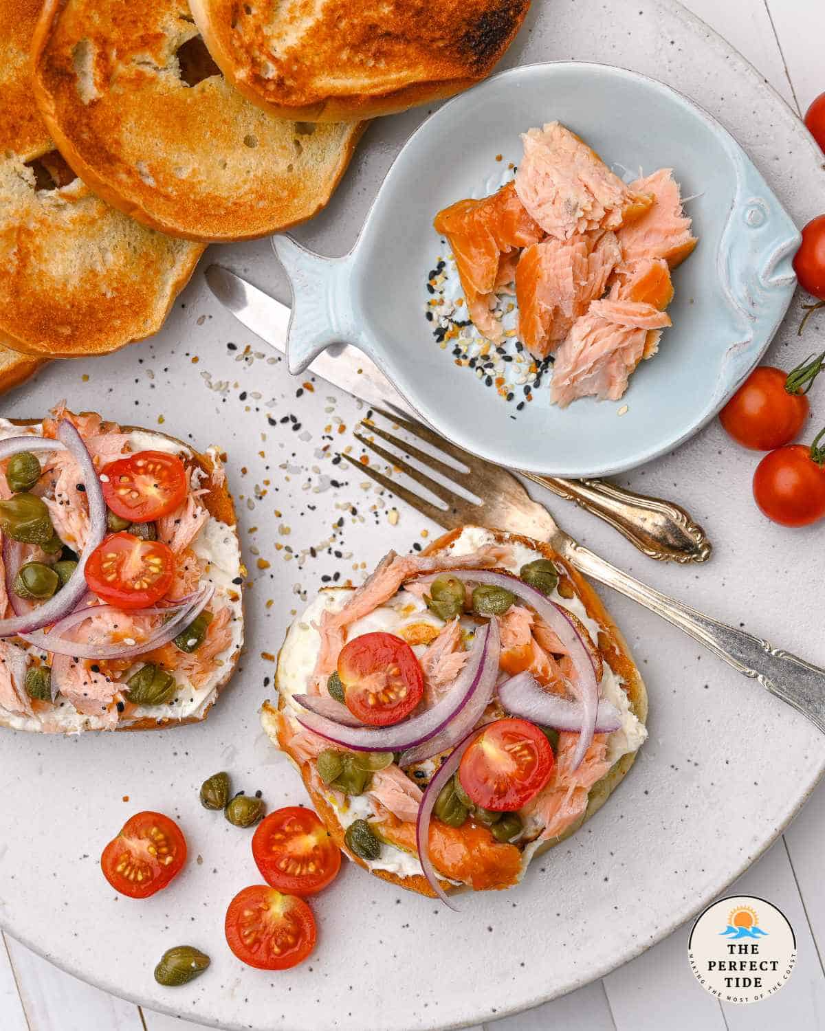 bagel with smoked salmon and egg cherry tomatoes capers and red onion with a side of extra smoked salmon and bagels