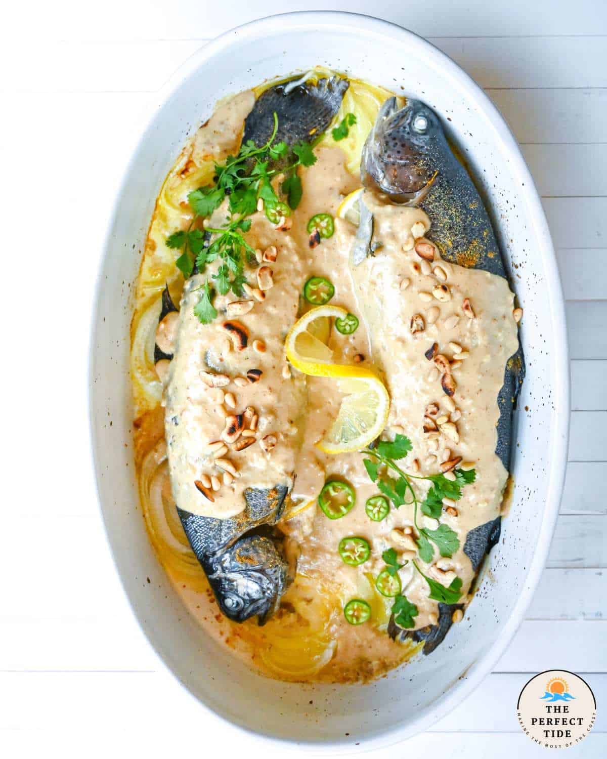whole fish with harra sauce in a oval white baking dish called samke harra