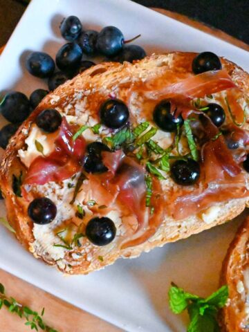 blueberry toast with prosciutto and goat cheese and herbs