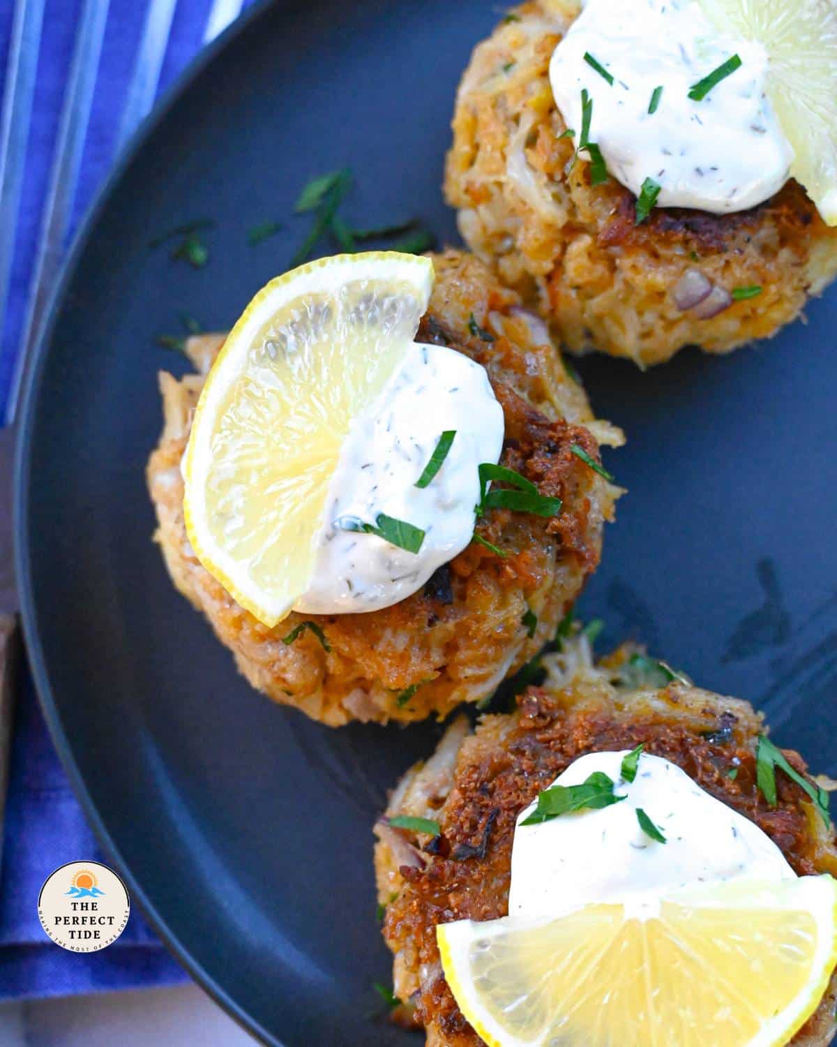 crab cakes on plate with tartar sauce and lemon
