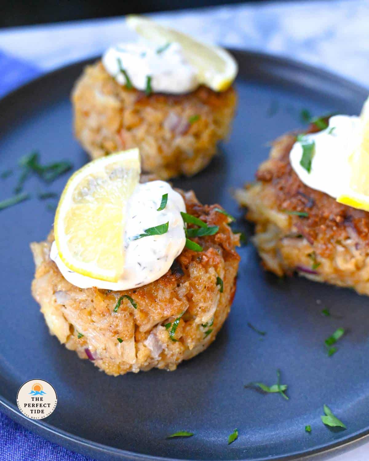 crab cakes on plate with tartar sauce and lemon