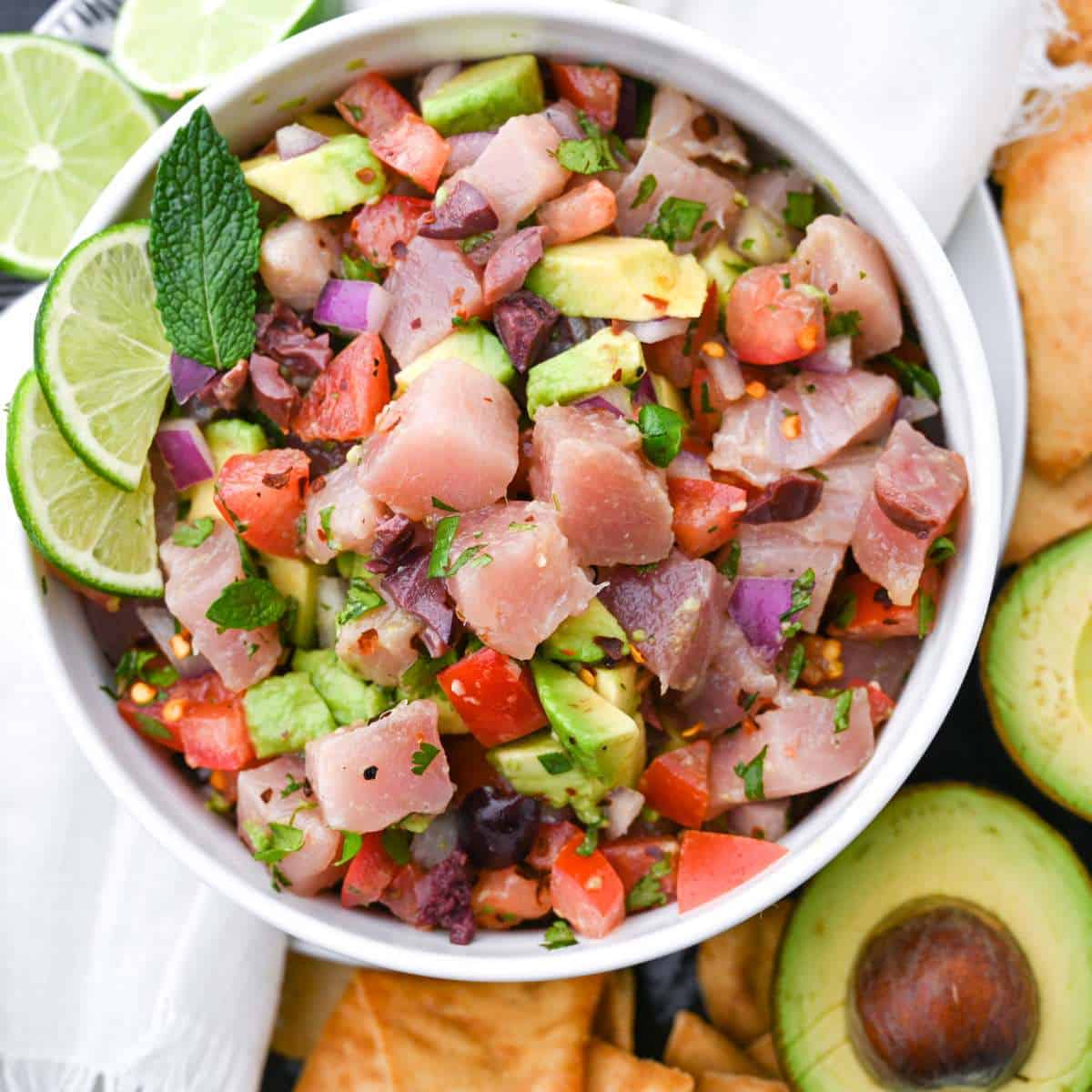 tuna ceviche in a white bowl with avocado and lime