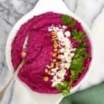 pink hummus with beets garnished with feta walnuts and parsley
