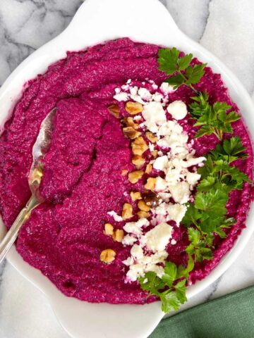 pink hummus with beets garnished with feta walnuts and parsley