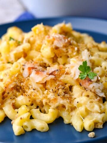 crab and mac and cheese topped with breadcrumbs and parsley on a blue plate