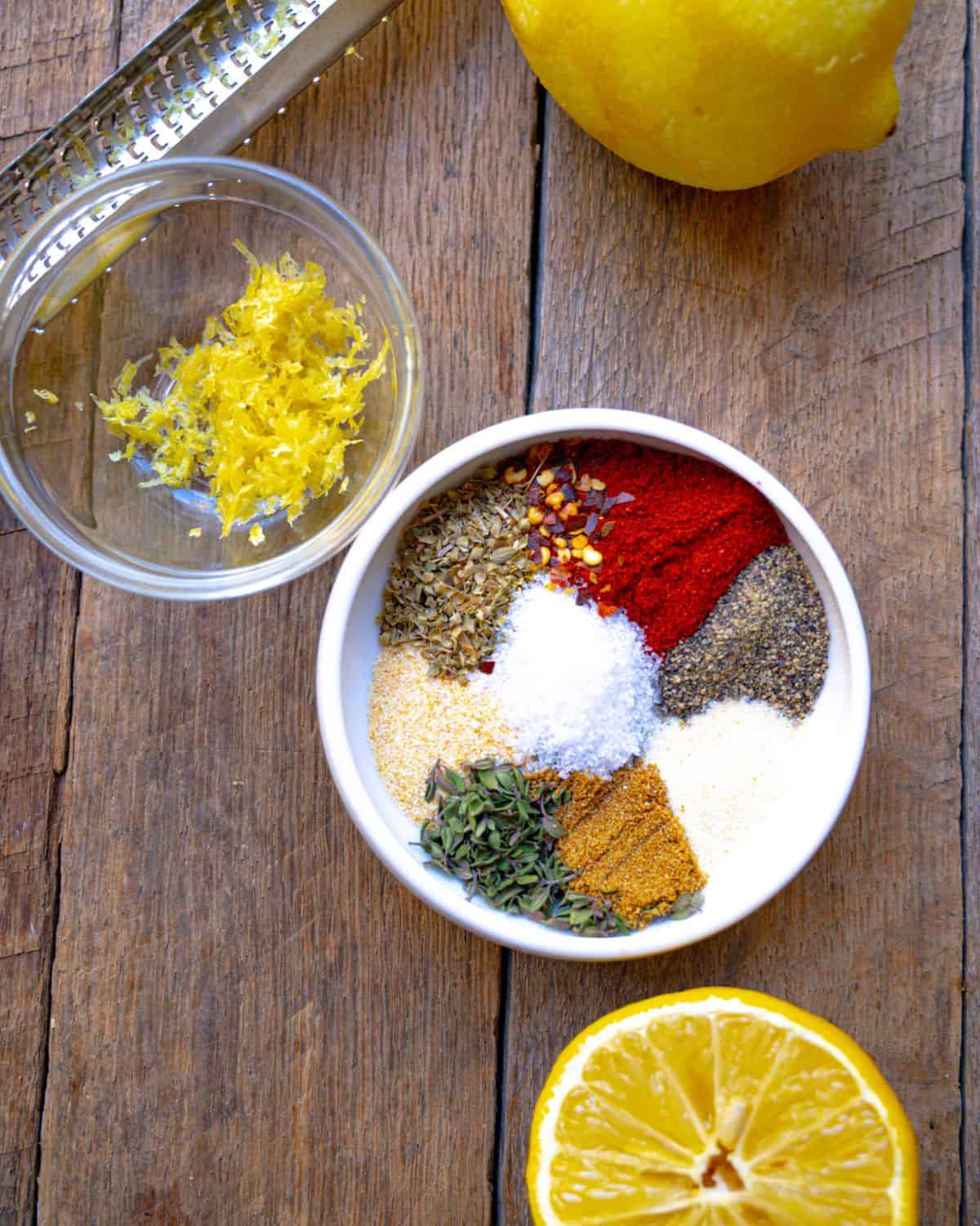 salmon rub recipe ingredients in a white dish with lemon zest and lemon nearby