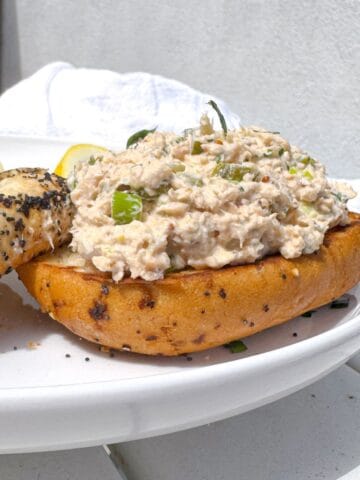 canned salmon salad recipe on a toasted bagel on a white place