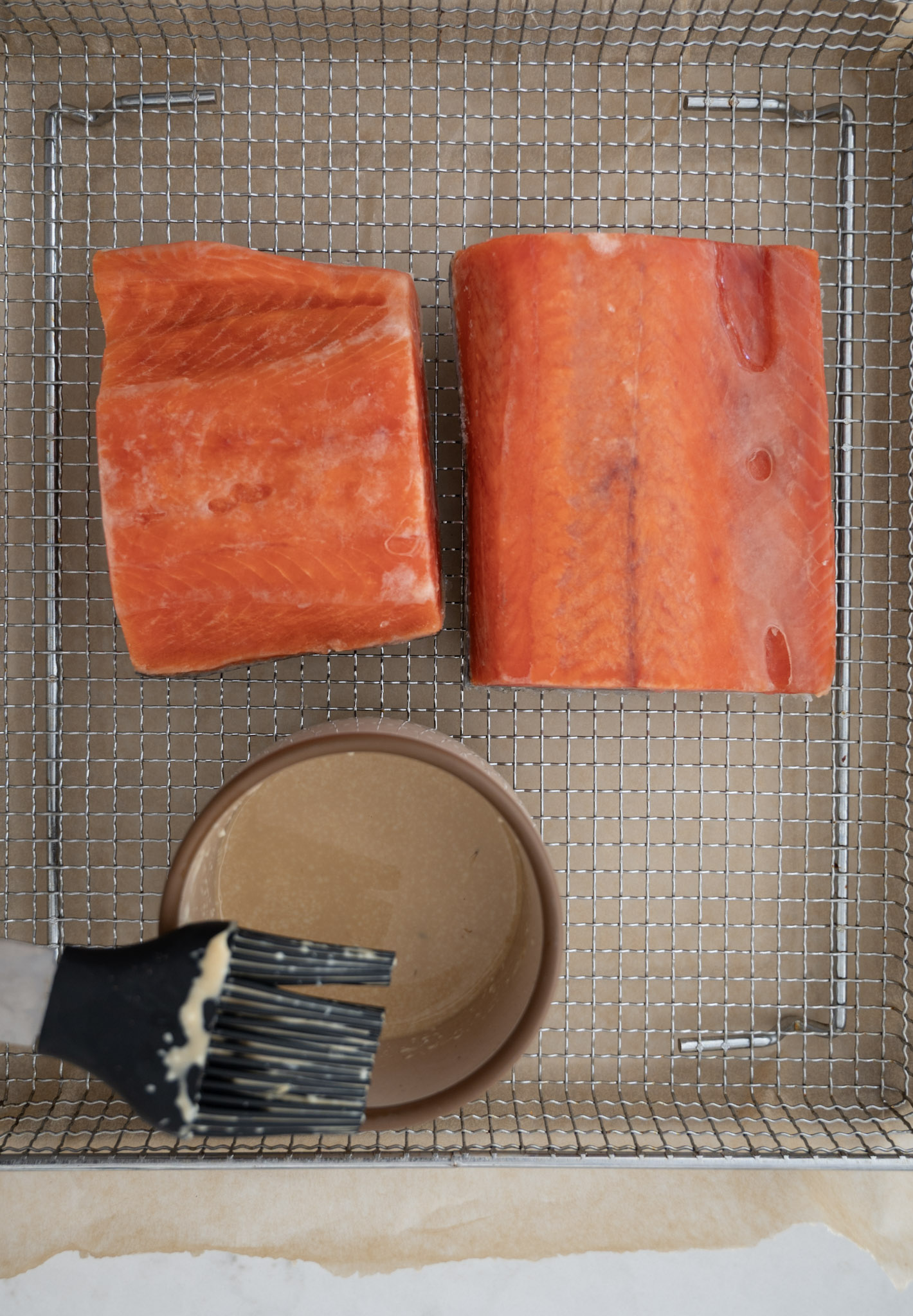 frozen salmon in air fryer next to small bowl of sauce
