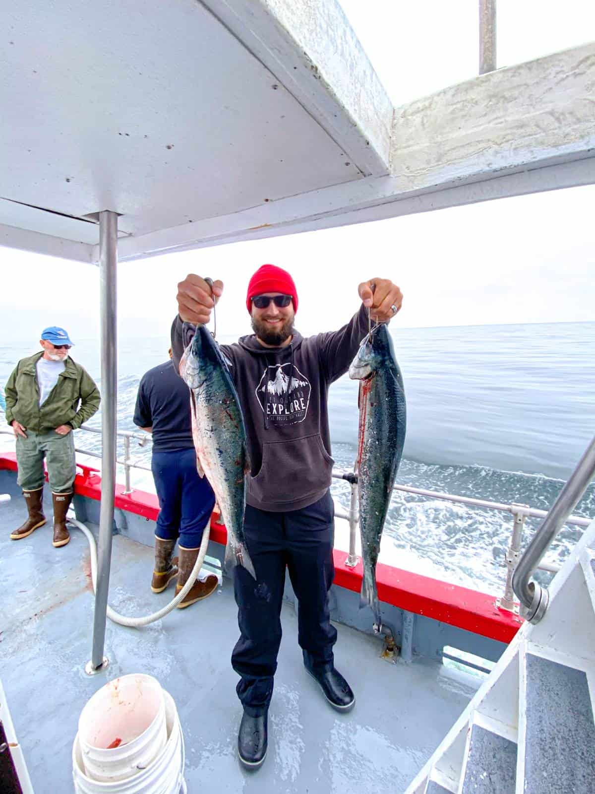 man on a fishing charter  holding 2 large salmon for post on deep sea fishing charter packing list